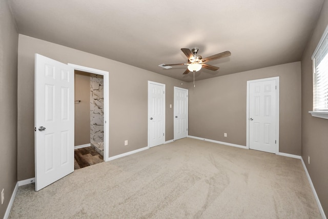 unfurnished bedroom featuring two closets, ensuite bath, ceiling fan, and carpet flooring