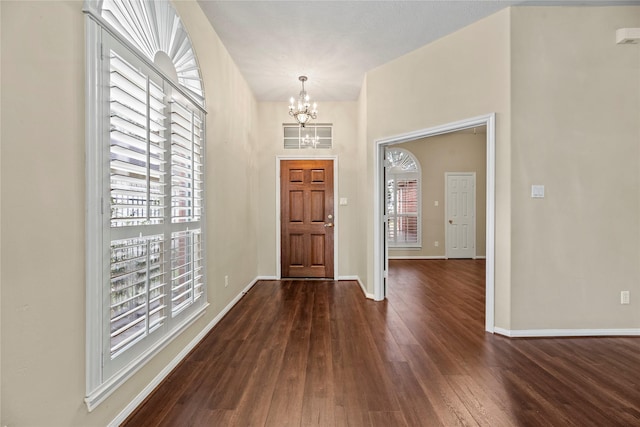 foyer entrance featuring an inviting chandelier and dark wood-type flooring