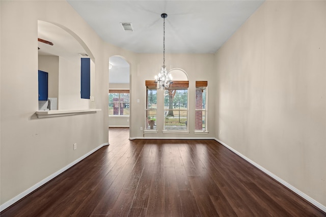 empty room featuring dark wood-type flooring and a chandelier