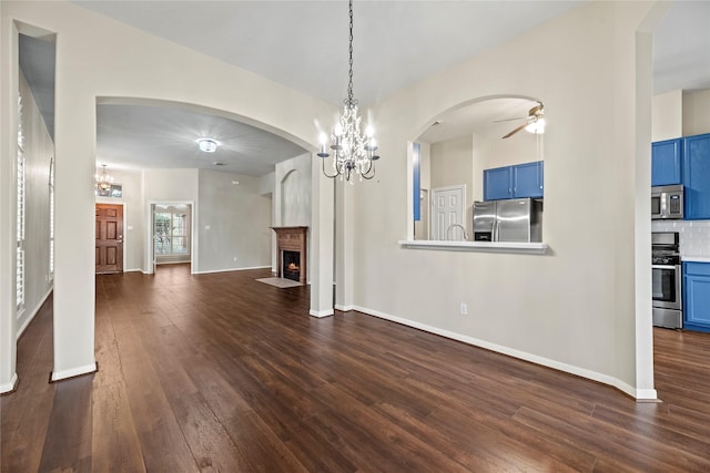 unfurnished living room featuring dark hardwood / wood-style floors and ceiling fan with notable chandelier