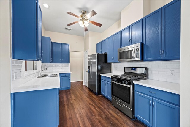 kitchen featuring appliances with stainless steel finishes, sink, dark hardwood / wood-style flooring, ceiling fan, and blue cabinetry