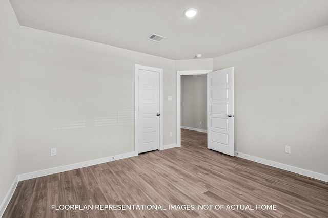 unfurnished room with visible vents, baseboards, and wood finished floors