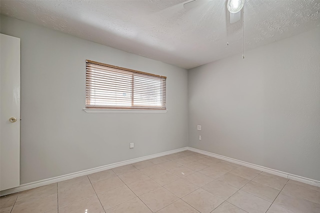 empty room with light tile patterned flooring, ceiling fan, and a textured ceiling