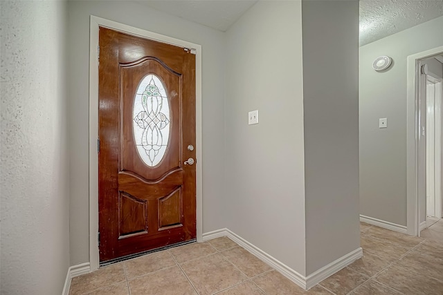 foyer entrance with light tile patterned floors and a textured ceiling