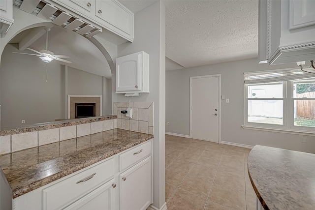 kitchen with white cabinetry, dark stone countertops, light tile patterned floors, and a textured ceiling