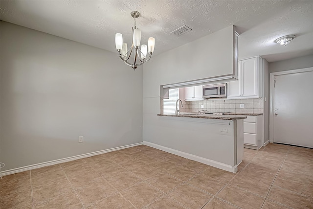 kitchen featuring pendant lighting, tasteful backsplash, a notable chandelier, white cabinets, and kitchen peninsula