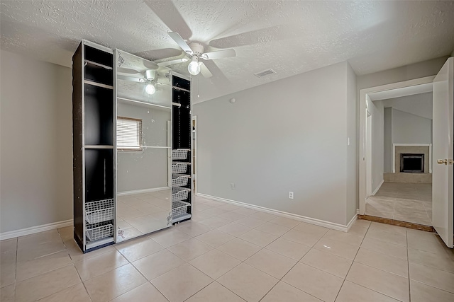 unfurnished bedroom with ceiling fan, a textured ceiling, and light tile patterned floors