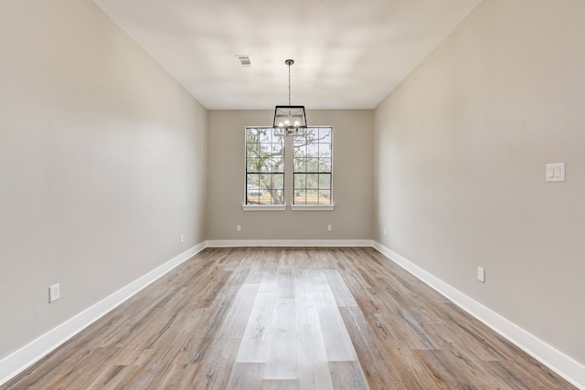 unfurnished dining area featuring light wood-type flooring and a chandelier