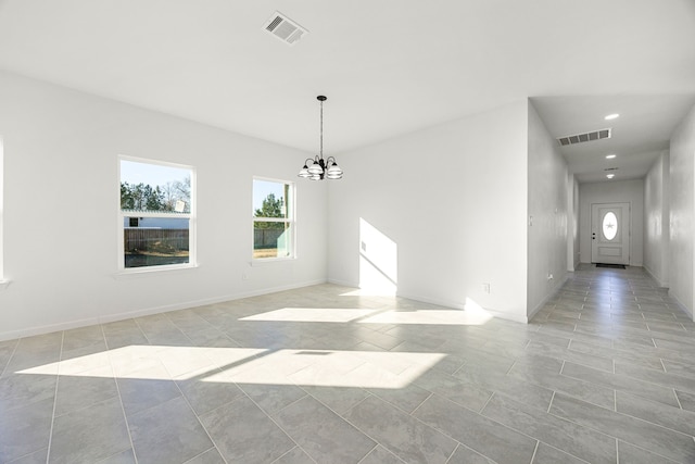 spare room with an inviting chandelier and light tile patterned floors