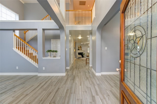 foyer entrance featuring a towering ceiling and light hardwood / wood-style floors