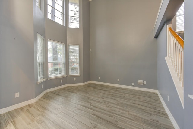 unfurnished room with hardwood / wood-style flooring, a healthy amount of sunlight, and a high ceiling