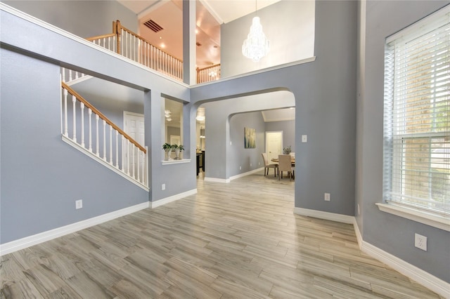 unfurnished living room featuring hardwood / wood-style flooring, a chandelier, and a high ceiling