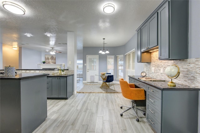 kitchen with light hardwood / wood-style flooring, gray cabinets, kitchen peninsula, pendant lighting, and decorative backsplash