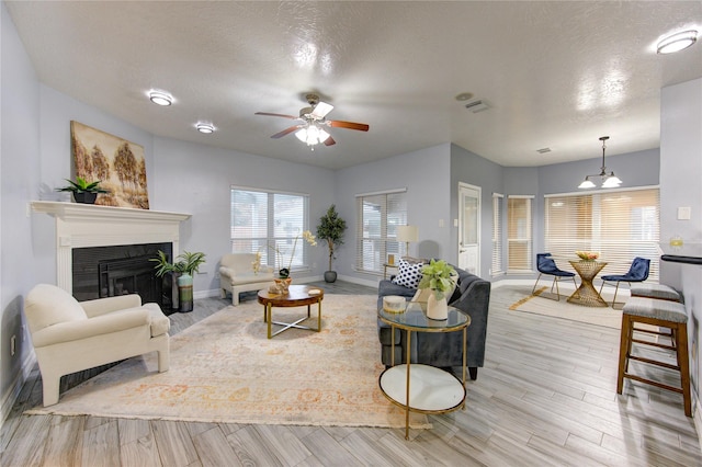 living room with a textured ceiling, light hardwood / wood-style flooring, and ceiling fan