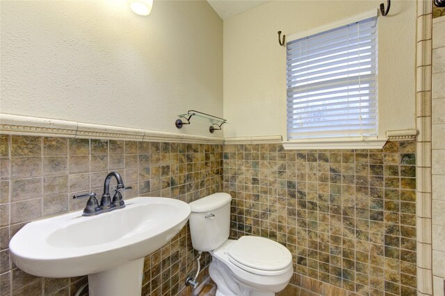 bathroom with tile walls, sink, and toilet