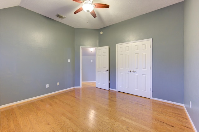 unfurnished bedroom with ceiling fan, lofted ceiling, a closet, and light wood-type flooring