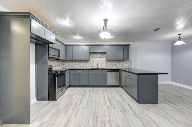 kitchen featuring pendant lighting, sink, gray cabinetry, kitchen peninsula, and stainless steel appliances