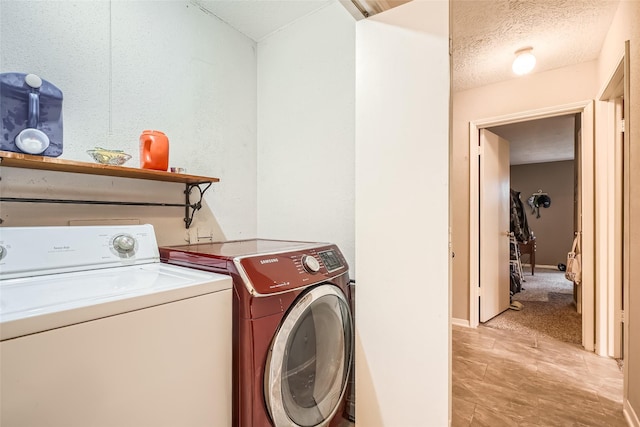 laundry area with washing machine and dryer and a textured ceiling