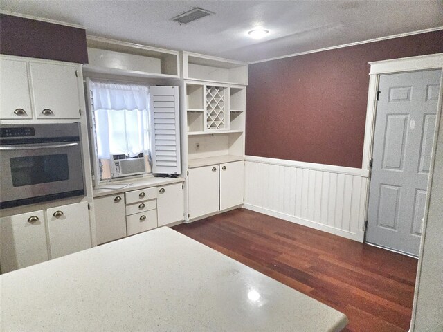 kitchen with ornamental molding, dark hardwood / wood-style flooring, cooling unit, oven, and white cabinets