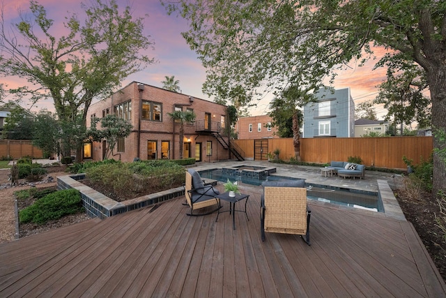 deck at dusk with a pool with hot tub