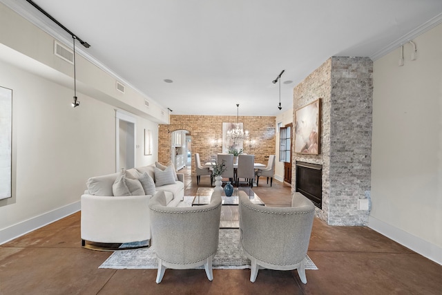 living room with an inviting chandelier, a fireplace, ornamental molding, and brick wall