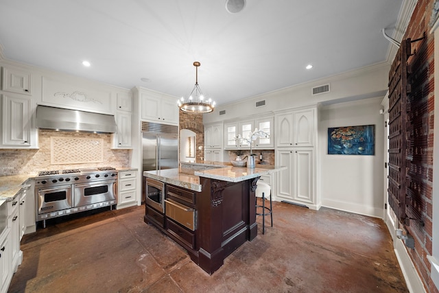 kitchen featuring range hood, white cabinets, a kitchen breakfast bar, a center island, and built in appliances