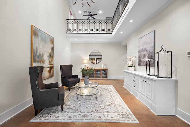 sitting room featuring light wood-type flooring, ceiling fan, and a high ceiling