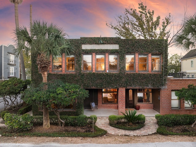 back house at dusk featuring a patio