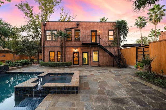 back house at dusk with a pool with hot tub and a patio area