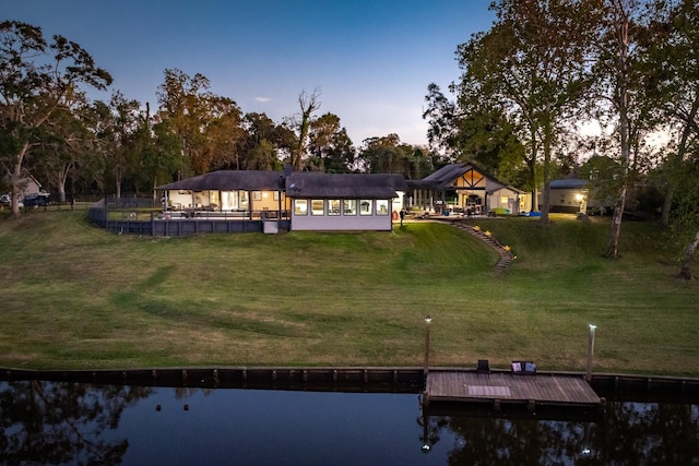 back house at dusk with a gazebo, a water view, and a yard