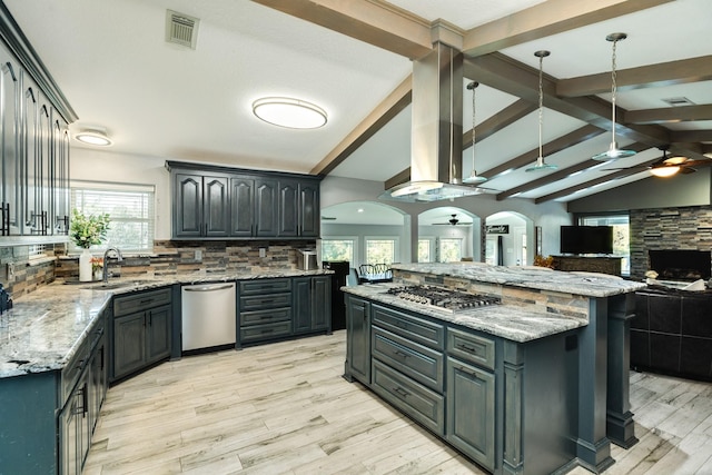 kitchen with pendant lighting, stainless steel appliances, range hood, light stone counters, and a kitchen island