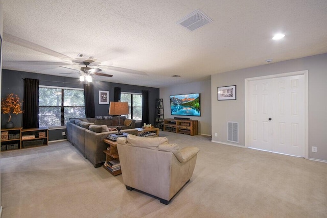 living room featuring light carpet, ceiling fan, and a textured ceiling