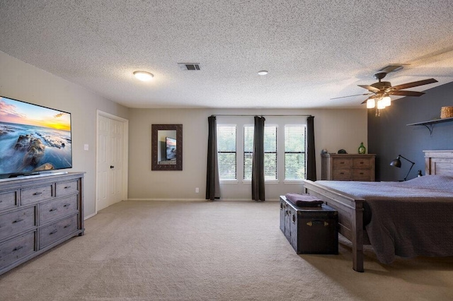 carpeted bedroom with ceiling fan and a textured ceiling