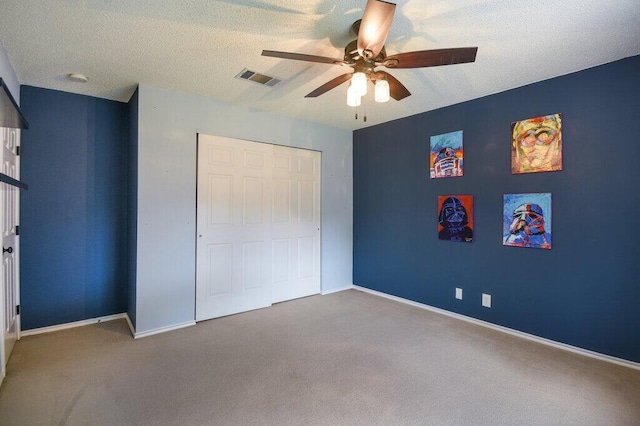 unfurnished bedroom featuring ceiling fan, a closet, carpet floors, and a textured ceiling