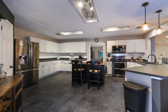 kitchen featuring white cabinetry, hanging light fixtures, a breakfast bar, and appliances with stainless steel finishes