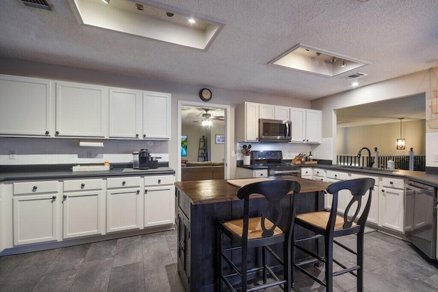 kitchen with pendant lighting, tasteful backsplash, white cabinets, and appliances with stainless steel finishes