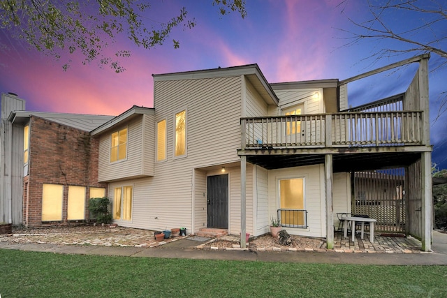 back house at dusk featuring a patio area, a yard, and a wooden deck