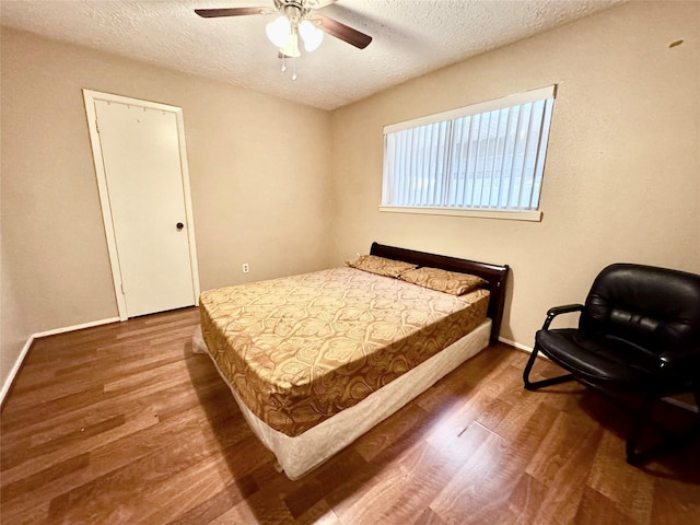 bedroom with ceiling fan, hardwood / wood-style floors, and a textured ceiling