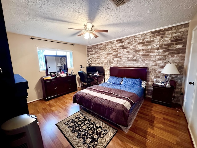 bedroom with hardwood / wood-style floors, brick wall, a textured ceiling, and ceiling fan