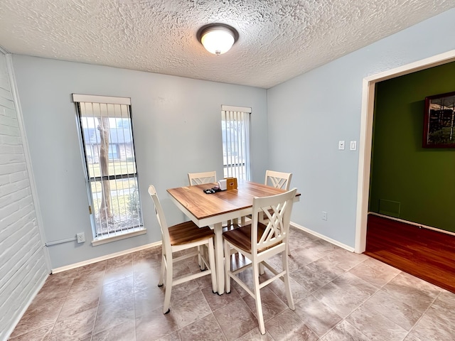 dining room with baseboards and a textured ceiling