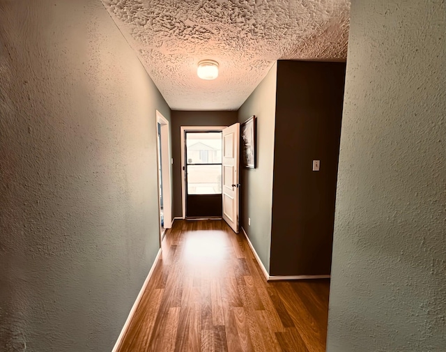 hallway with hardwood / wood-style flooring and a textured ceiling