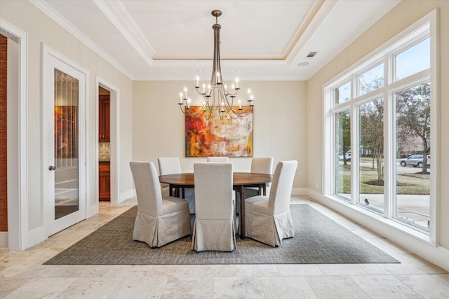 dining space with a raised ceiling, crown molding, and an inviting chandelier