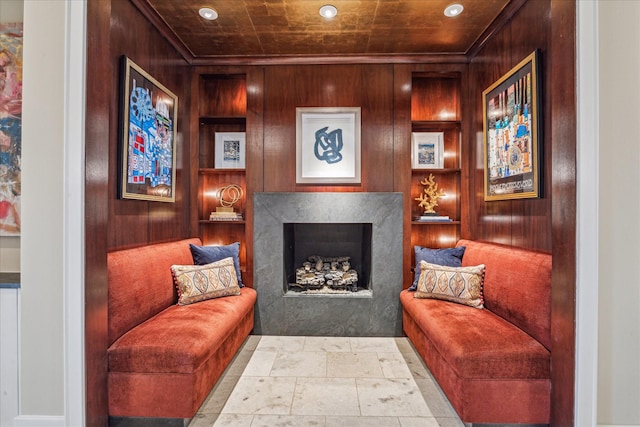 living area featuring a high end fireplace and wood walls