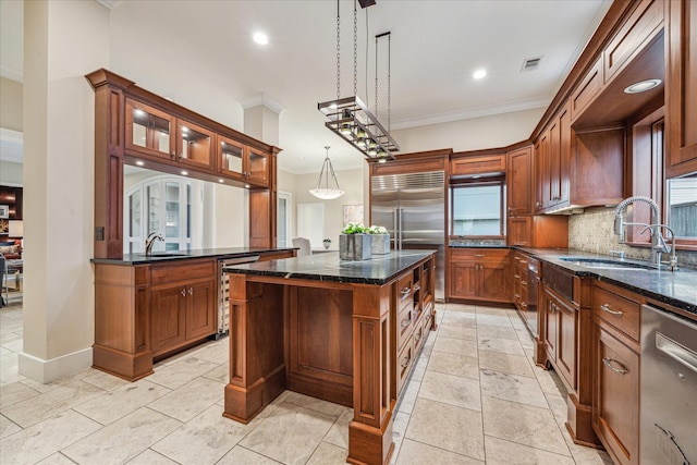 kitchen with sink, appliances with stainless steel finishes, dark stone countertops, hanging light fixtures, and a kitchen island