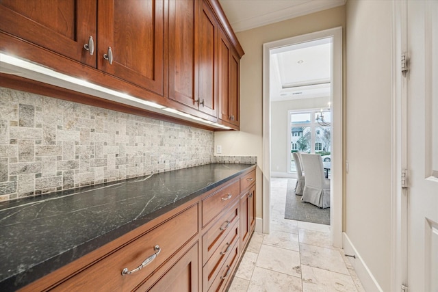 kitchen featuring crown molding, decorative backsplash, and dark stone counters