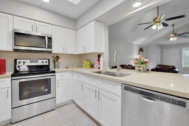 kitchen featuring sink, white cabinets, backsplash, light tile patterned floors, and stainless steel appliances