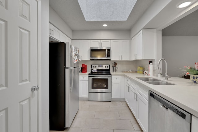 kitchen featuring light tile patterned flooring, sink, tasteful backsplash, appliances with stainless steel finishes, and white cabinets