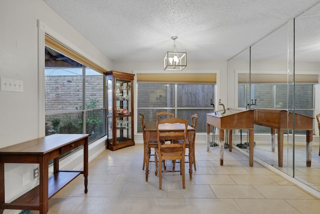 tiled dining room featuring a notable chandelier and a textured ceiling