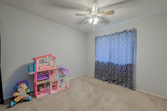 recreation room with ceiling fan, light carpet, and a textured ceiling