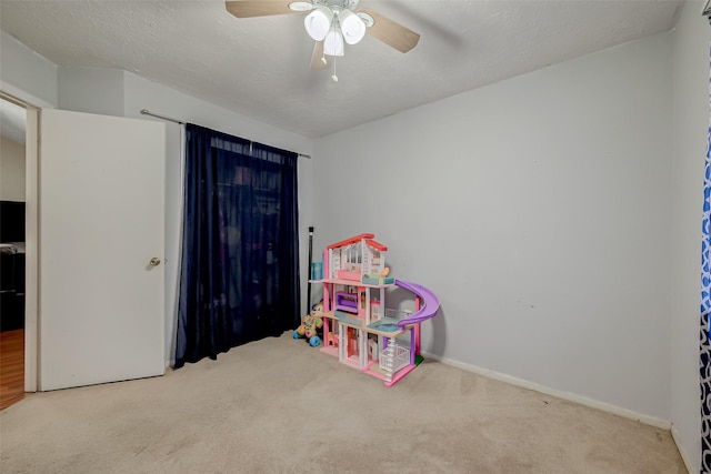 playroom with ceiling fan, carpet floors, and a textured ceiling